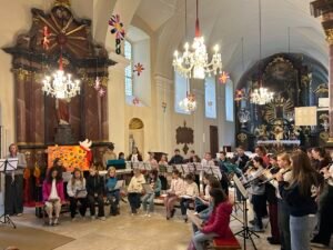 Chor und Orchester von Kindern und Jugendlichen musizieren in der barocken Kirche St. Michael in Bergheim bei Salzburg.